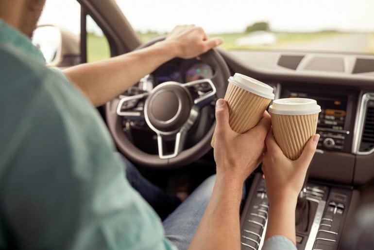 Couple driving with cups of coffee
