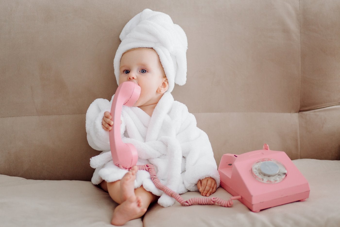 Cute baby playing with a pink vintage phone toy