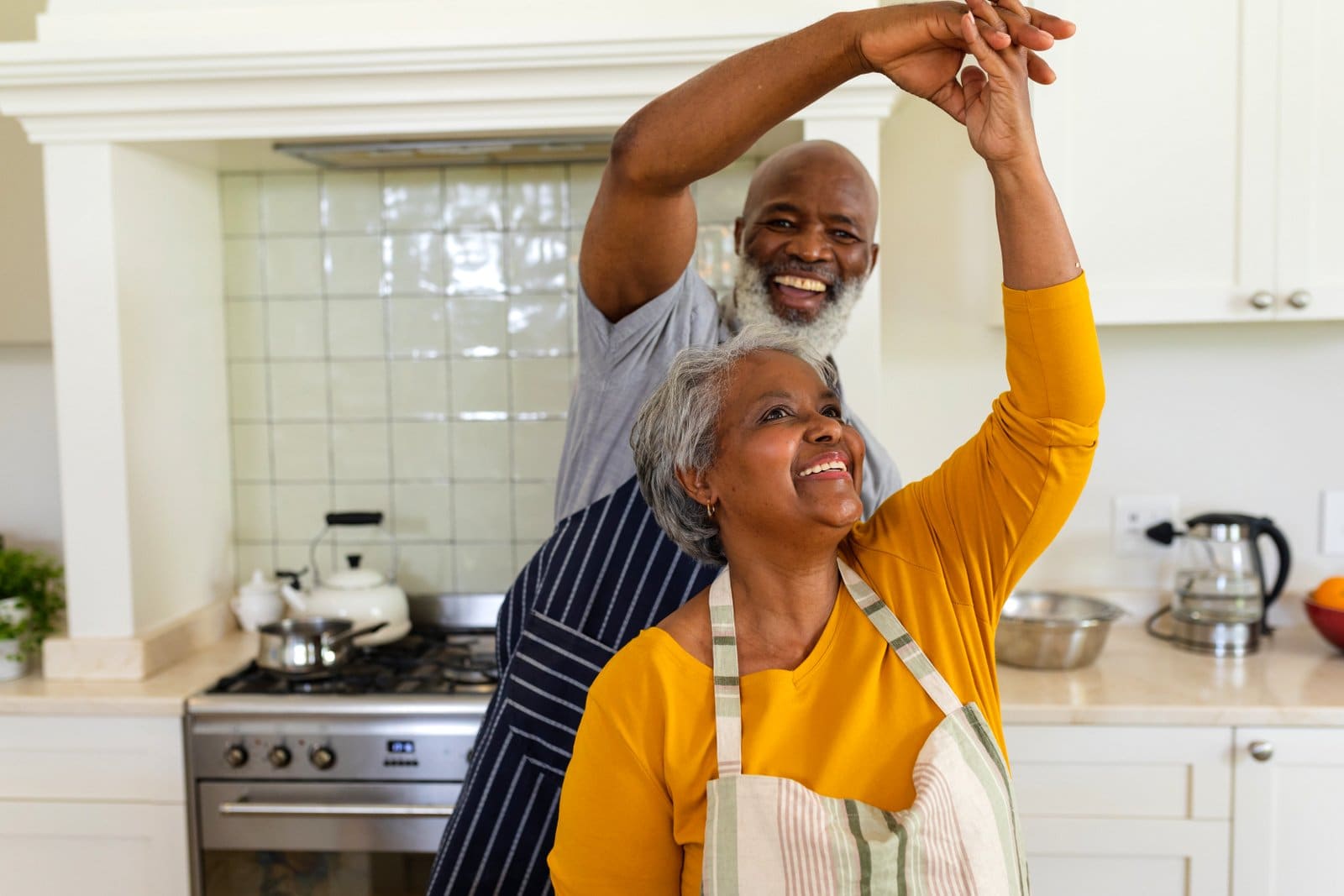 Brain health and prevent alzheimer's: Cute boomer couple dancing in their kitchen