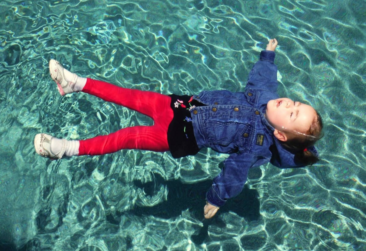 Girl rescuing herself in a pool wearing winter clothes