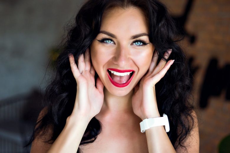 Happy smiling woman wearing lipstick and dark eyeliner