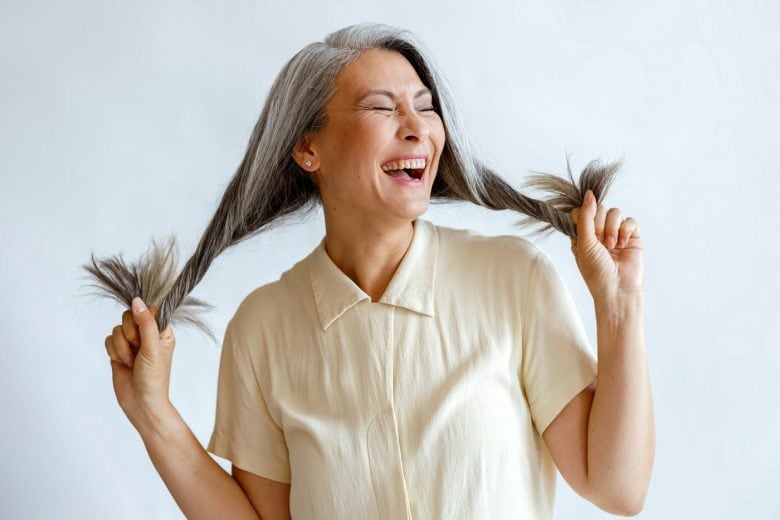 Happy woman holding her grey hair