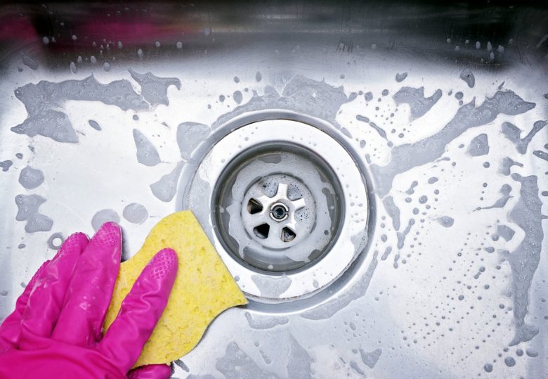 Kitchen sponge cleaning a stainless steel sink