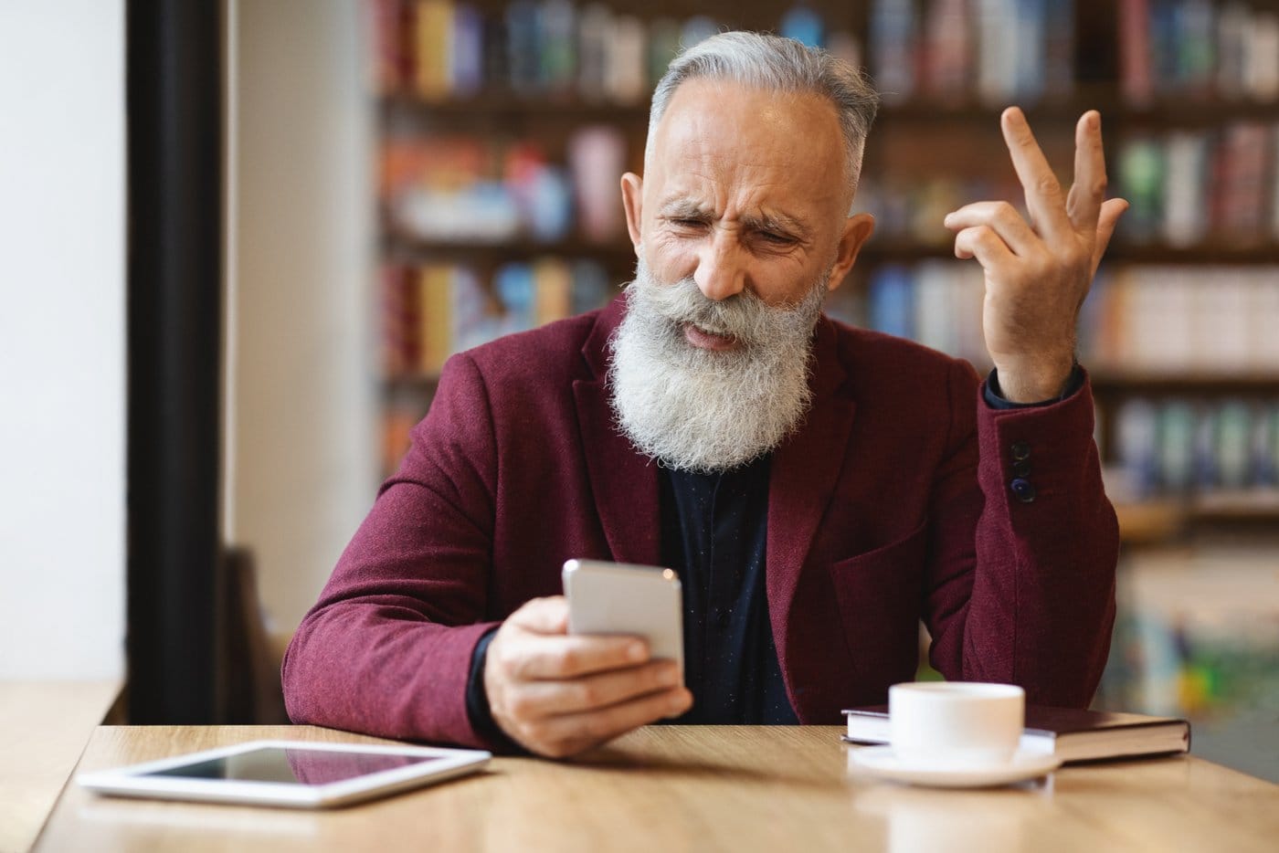 Angry man using mobile phone at cafe