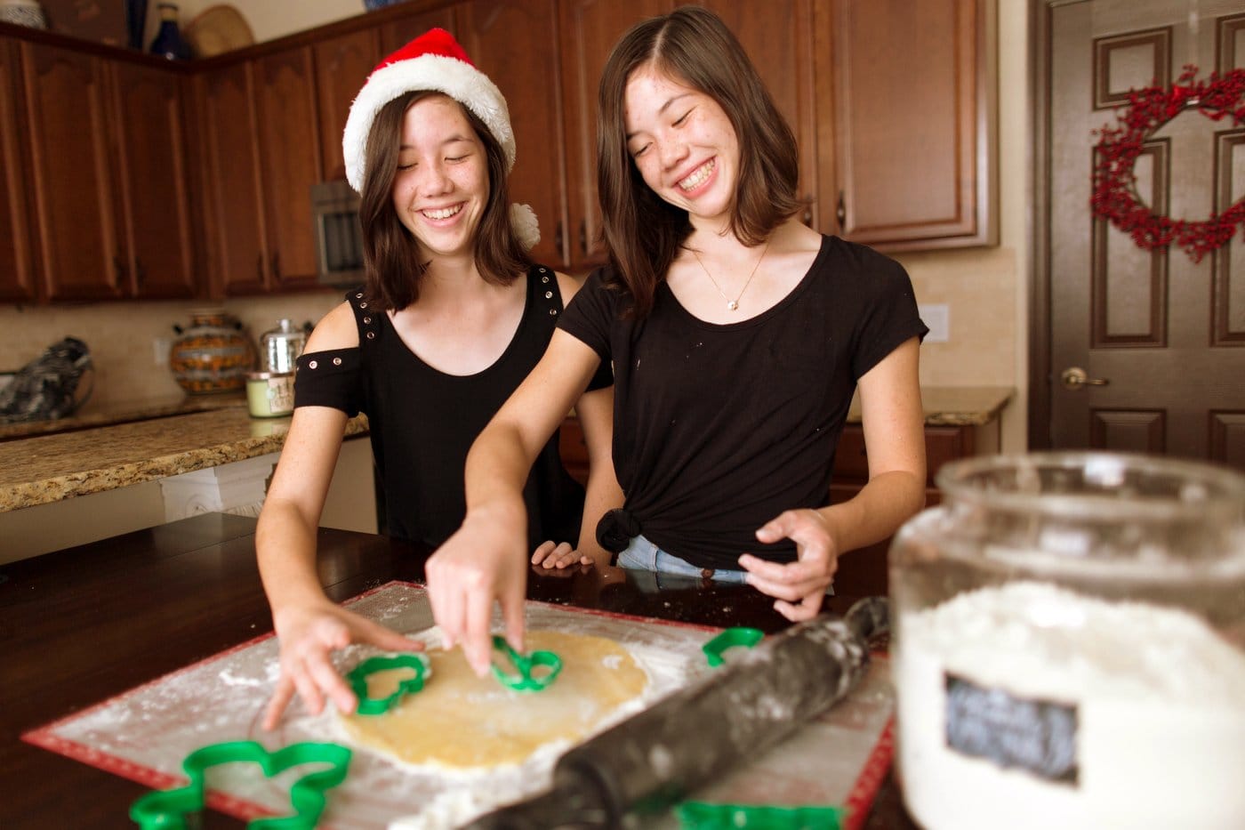 Teenage sisters baking Christmas cookies together