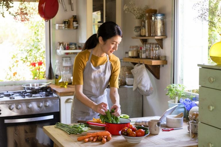 Woman cooking in the kitchen with lots of vegetables