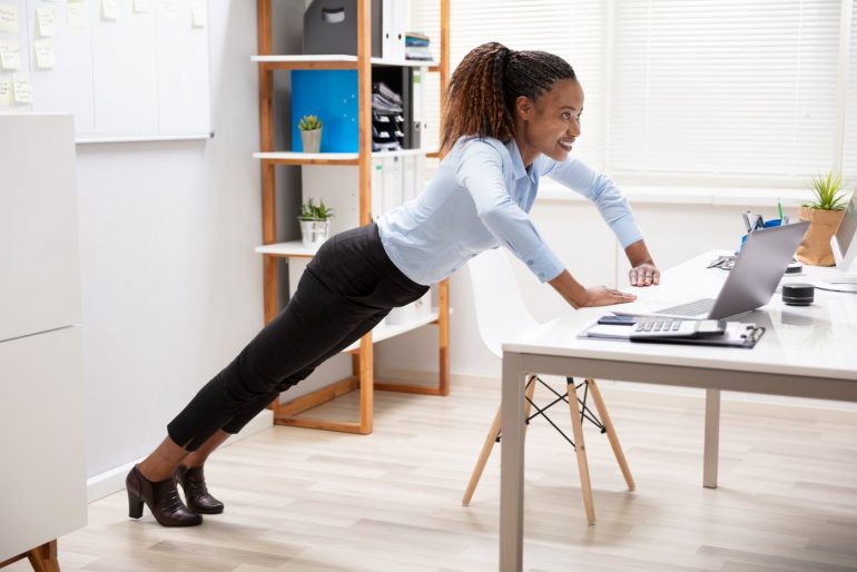 Woman doing a pushup on her office desk
