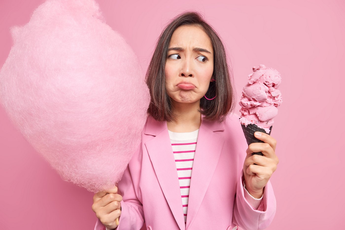 Woman eating carmine colored pink ice cream and cotton candy