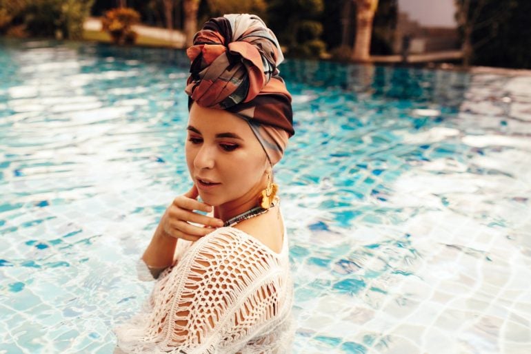 Woman in turban in the pool wearing summer makeup