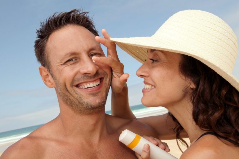 Woman putting sunscreen on a man's nose