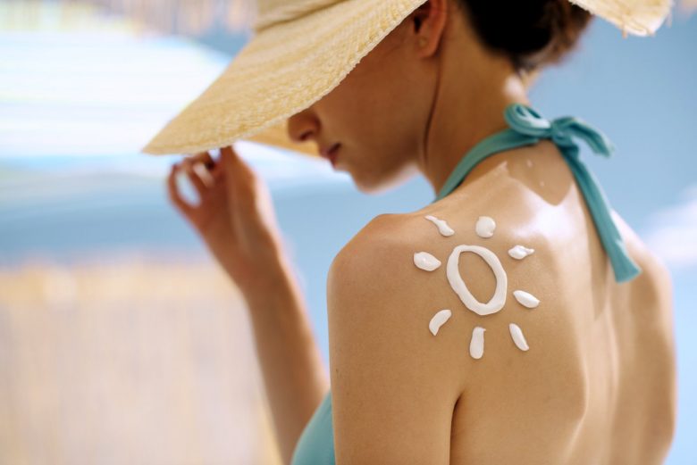 Woman with a sunscreen sun painted on her shoulder