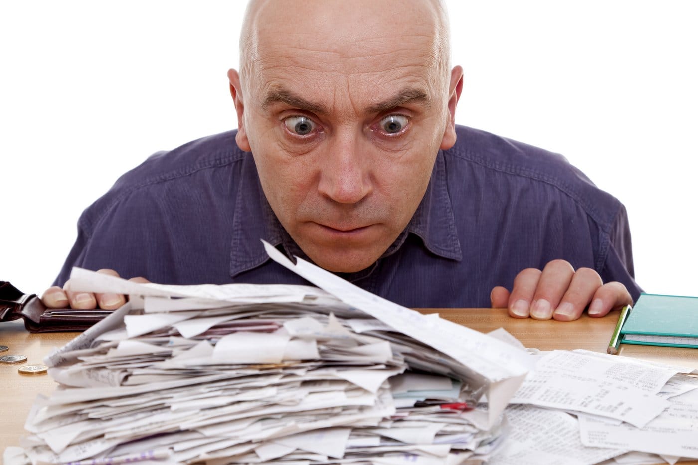 Worried man staring at pile of paper receipts