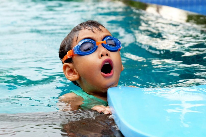 boy swimming in a pool with goggles